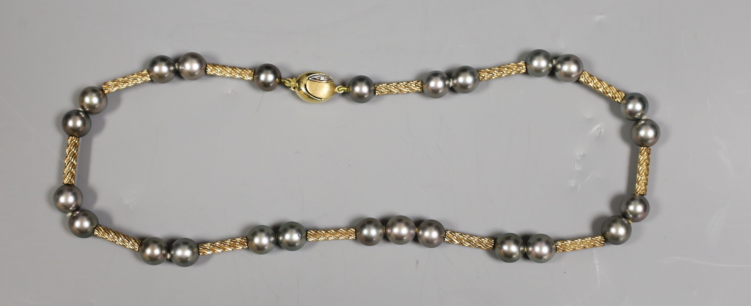 A cased modern 750 yellow metal and Tahitian? pearl set necklace, with diamond chip set clasp, 39cm, gross weight 31.1 grams.
